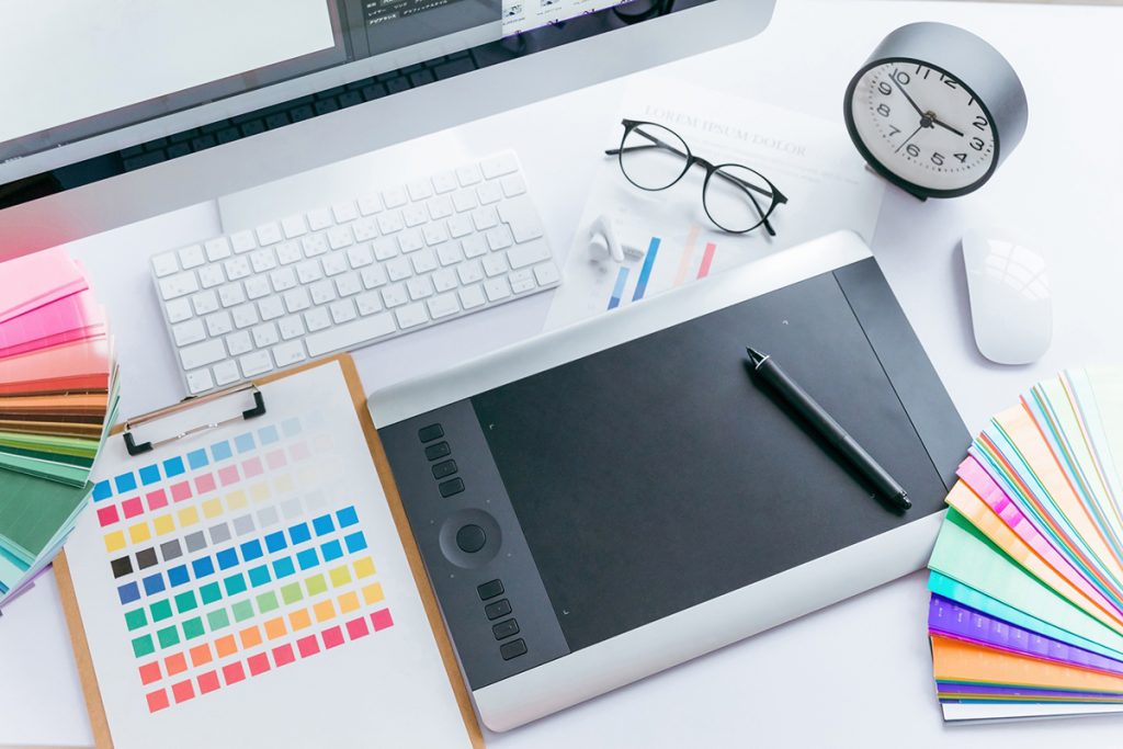 デザイン制作に使われるペンタブレットとカラーチップが並んだ作業デスク